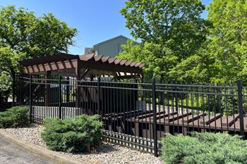 A gazebo in front of a fence with trees in the background